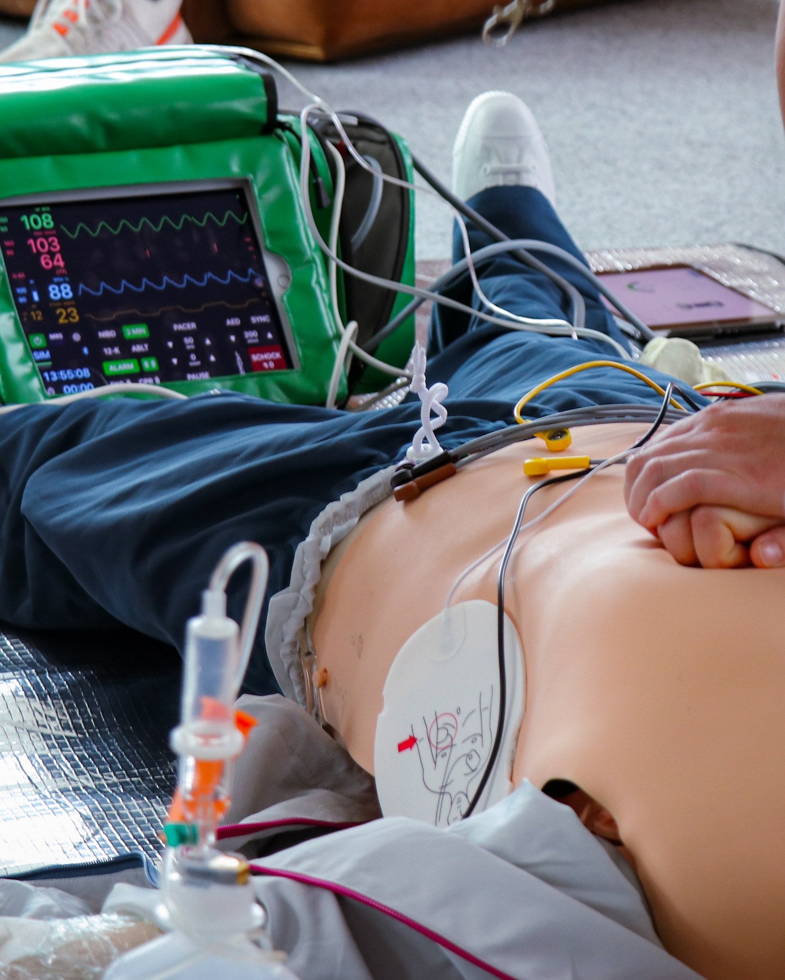 ACLS-Training bei MediCademy: Thoraxkompressionen am Simulator mit Defibrillator-Elektrode und Monitor mit Vitalwerten